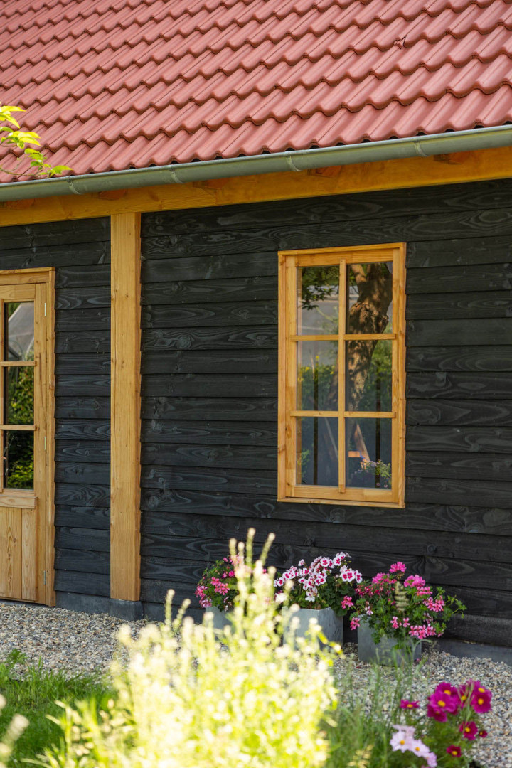 detail-van-zwarte-houten-gevel-met-houten-deur-en-raam-bij-zadeldak-xxl