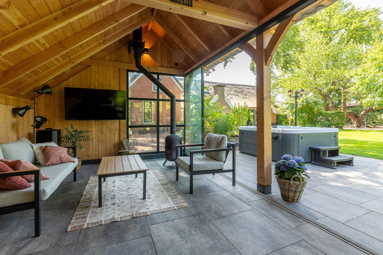 binnenaanzicht-van-kapschuur-de-hoeve-met-douglas-constructie-zithoek-en-glazen-schuifwand-met-uitzicht-op-de-tuin