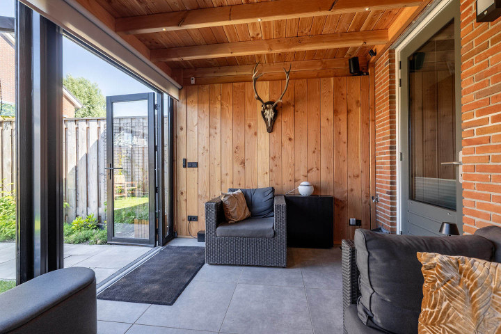 interieur-van-aanbouw-veranda-ancona-met-glazen-wanden-zithoek-en-houten-plafond-aan-de-woning
