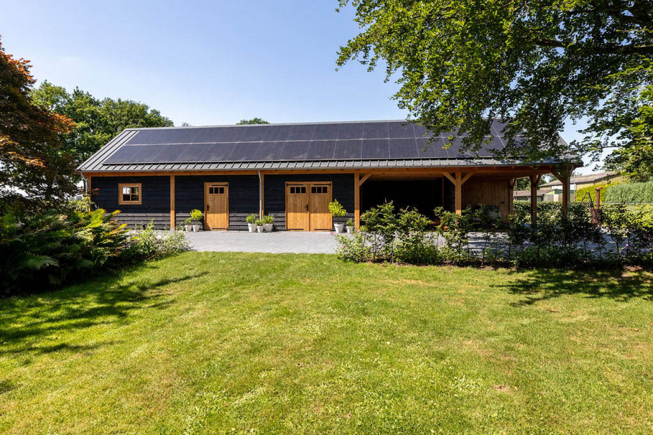 zijaanzicht-van-zadeldak-xxl-met-douglas-constructie-wanden-van-douglas-potdekselplanken-douglas-opgeklampte-deuren-en-open-overkapping-in-de-tuin