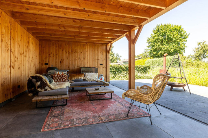 binnenzijde-van-open-overkapping-bij-zadeldak-xxl-met-douglas-constructie-zithoek-en-buitenruimte-met-uitzicht-op-de-tuin