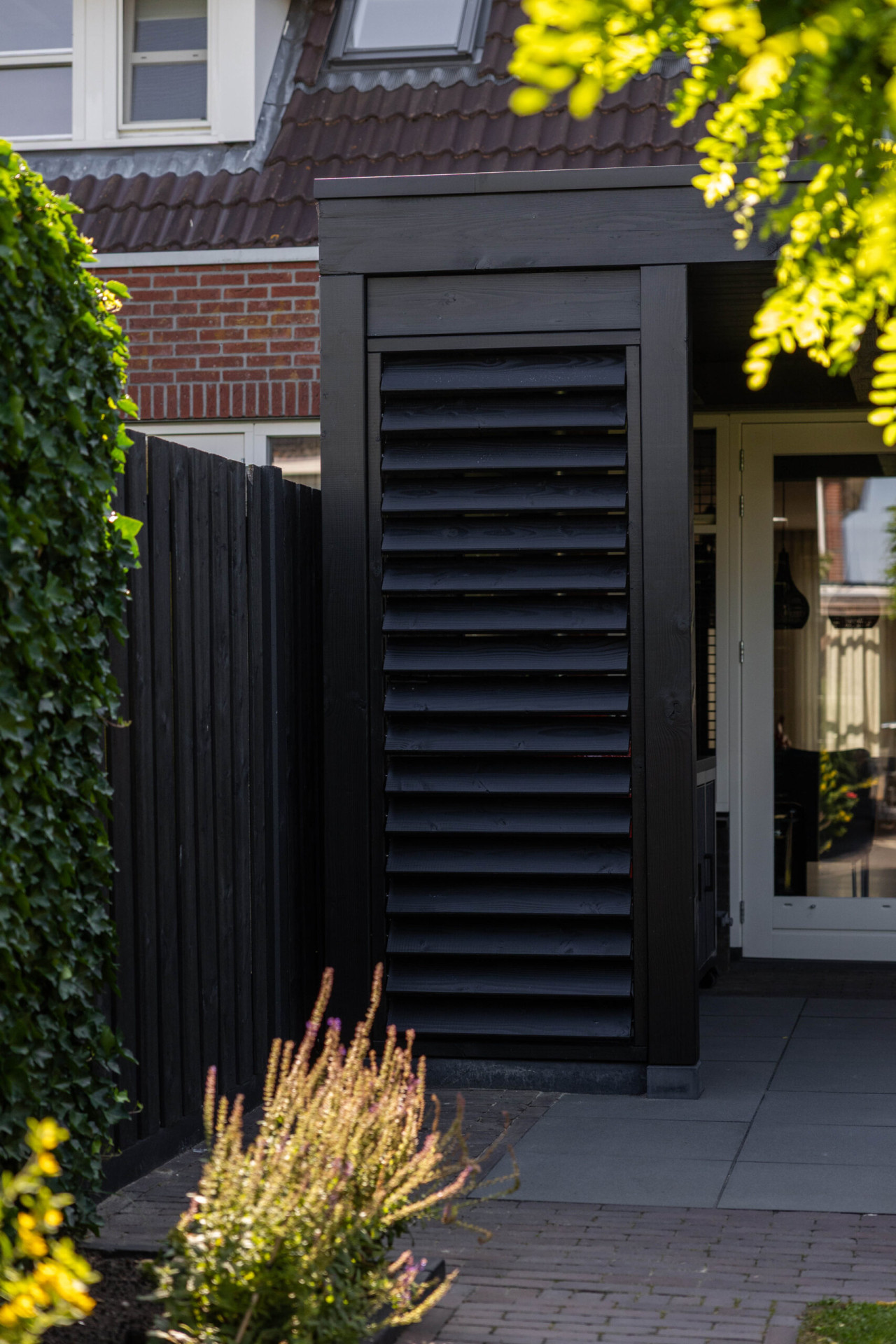 detail-van-louvre-wand-bij-aanbouwveranda-modena-met-zwarte-houten-wanden-aan-de-woning-in-de-tuin