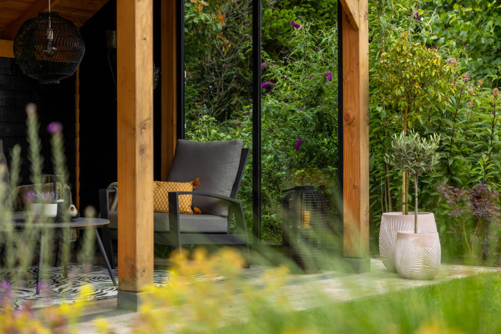 detail-van-douglas-houten-kapschuur-met-staanders-glazen-schuifwand-en-zitgedeelte-in-een-groene-tuin