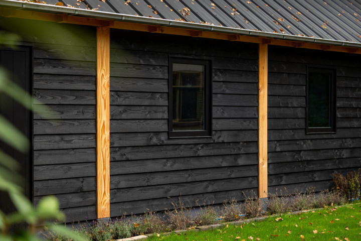 detail-van-zwarte-houten-wand-met-hardhouten-raam-en-douglas-balken-bij-zadeldak-select-landelijk