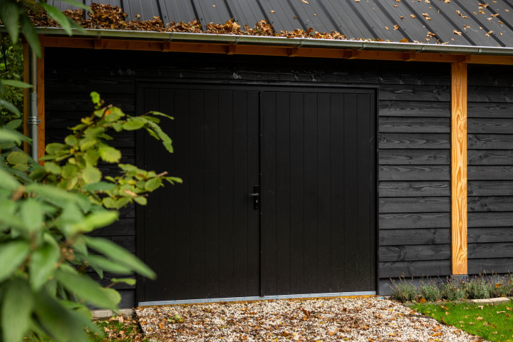 detail-van-hardhouten-plaatdeur-dubbel-xl-in-zadeldak-select-landelijk-met-zwarte-houten-wanden-en-douglas-constructie