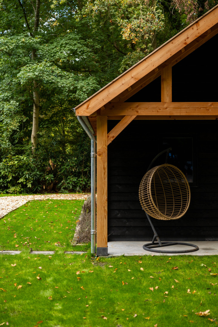 detail-van-dakoverstek-van-zadeldak-select-landelijk-met-douglas-constructie-en-hangstoel-in-de-tuin