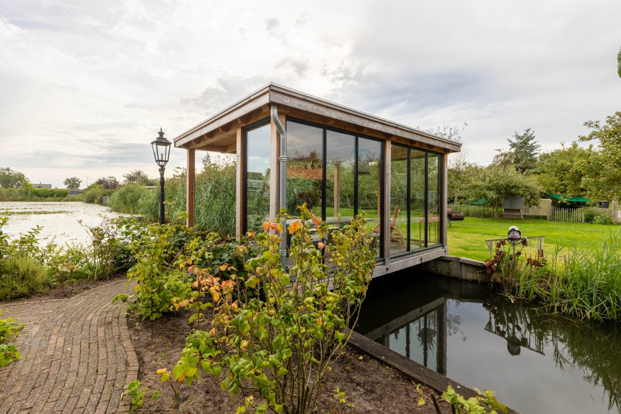 achteraanzicht-van-lichte-en-open-tuinkamer-overkapping-siena-met-glazen-wanden-op-vlonder-aan-het-water-in-de-tuin