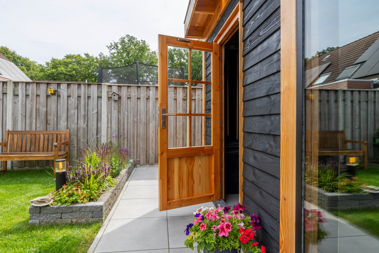 detail-van-houten-deur-van-modern-tuinhuis-met-zwarte-houten-gevel-en-terras-in-de-tuin