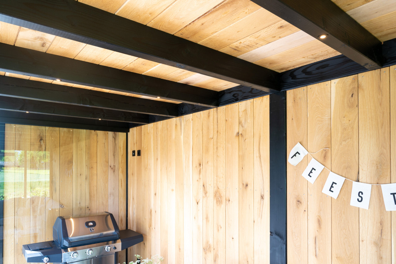 detail-van-zwarte-douglas-constructie-met-wanden-van-eiken-sponningsplanken-en-barbeque-in-overkapping-palermo