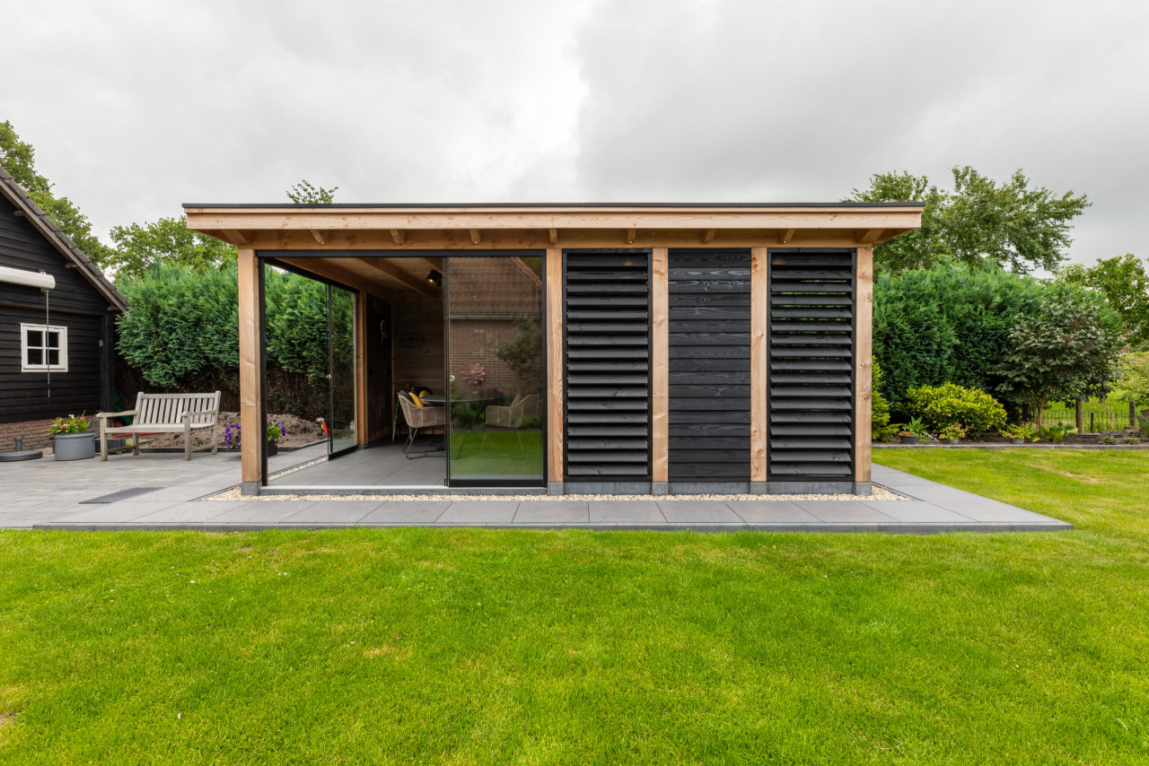 vooraanzicht-van-overkapping-florence-met-douglas-constructie-zwarte-potdekselplanken-louvres-glazen-schuifdeur-en-inbouwspots-in-de-tuin