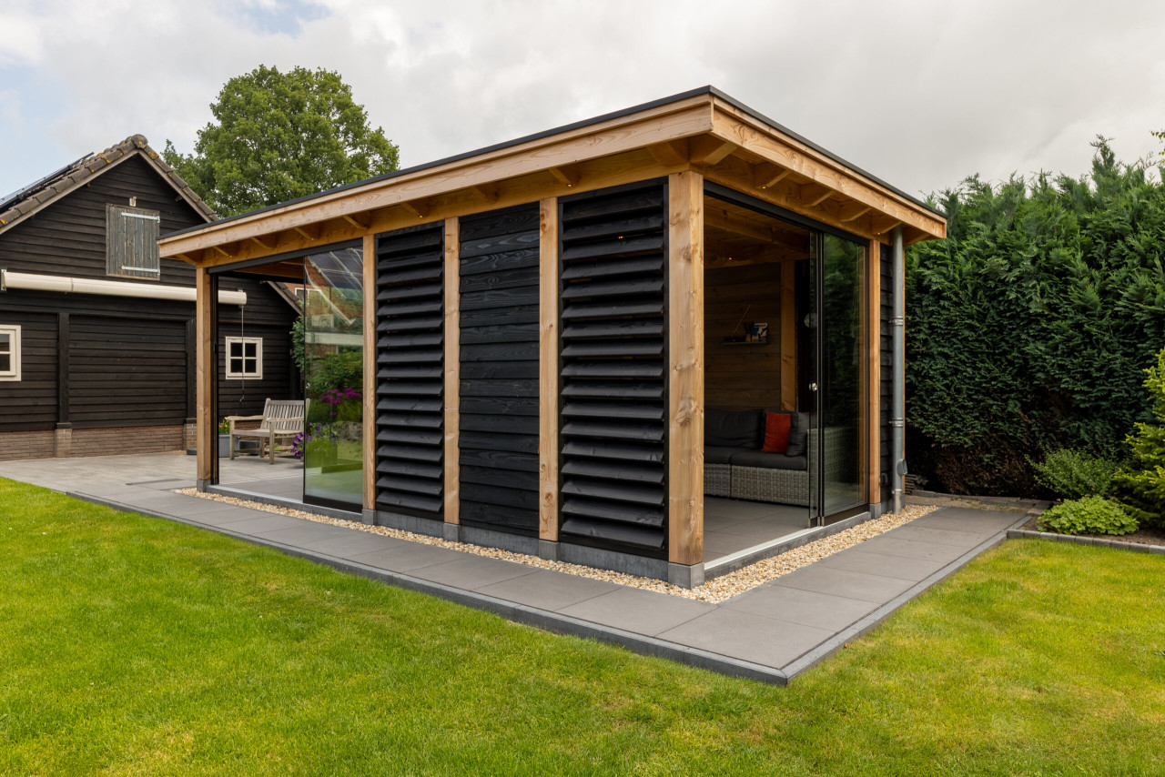 zijaanzicht-van-overkapping-florence-met-douglas-constructie-zwarte-potdekselplanken-louvres-glazen-schuifdeur-en-inbouwspots-in-de-tuin
